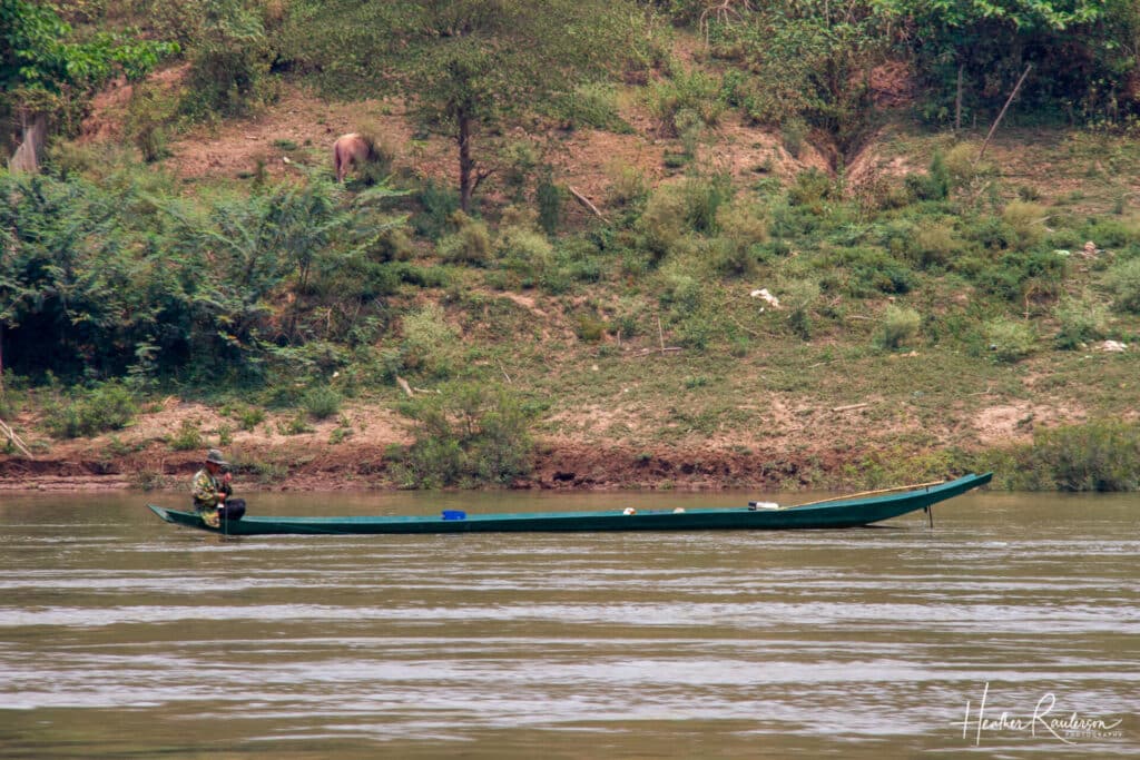 Fisherman on a Green Long Boat on the Mekong River