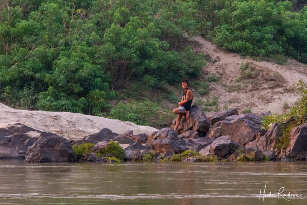 Laos man watching the slow boat from the banks of the Mekong River