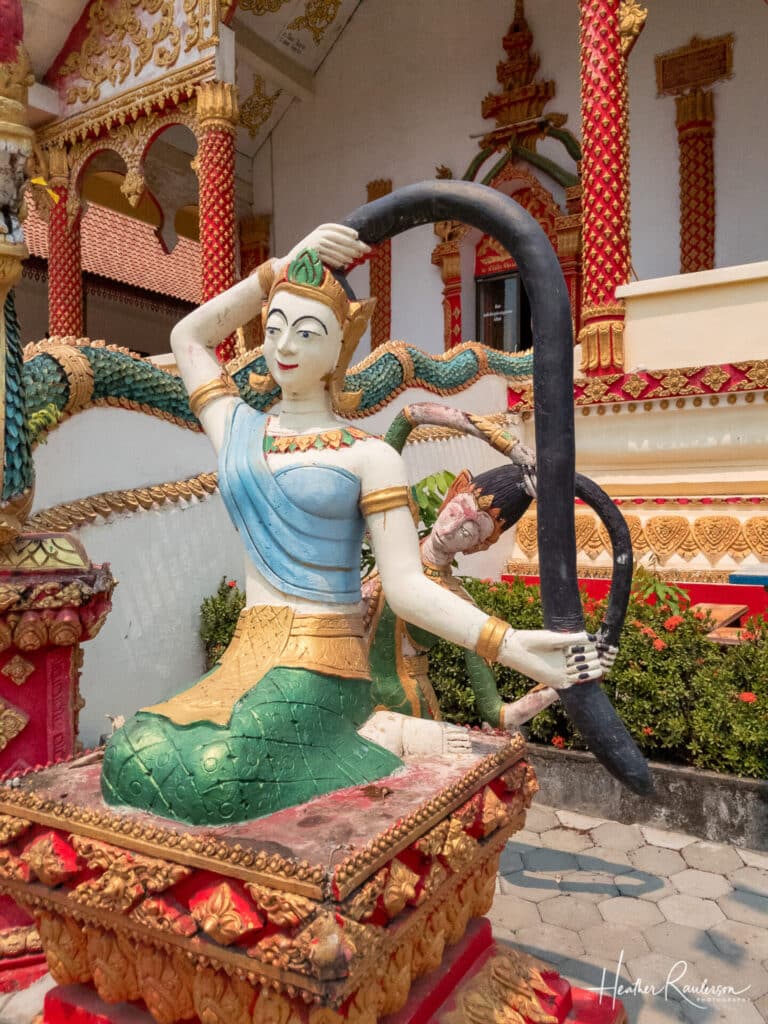 Statues holding pony tail in front of Wat That
